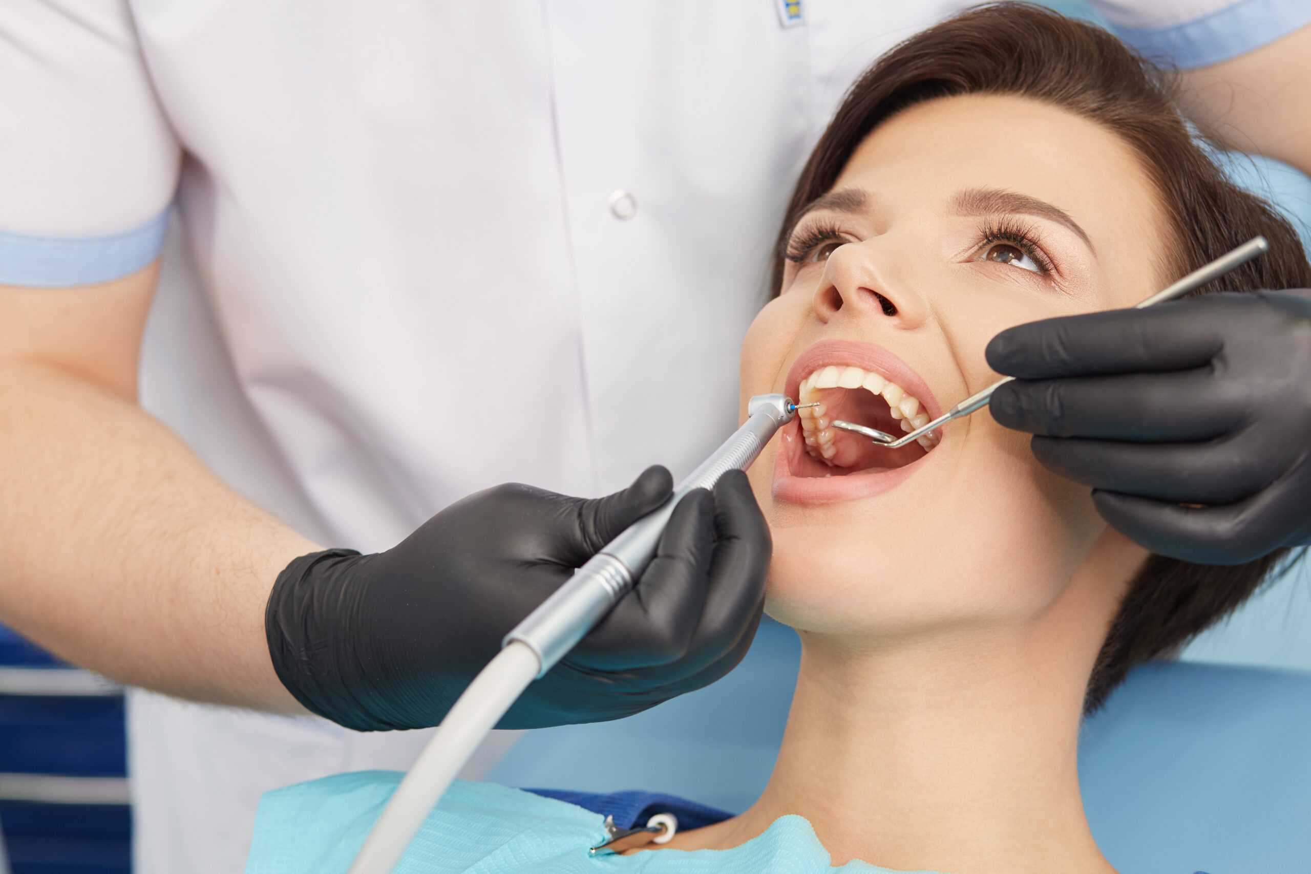 Young female patient visiting dentist office.Beautiful woman with healthy straight white teeth sitting at dental chair with open mouth during a dental procedure.Dental clinic.Stomatology.Dental caries prevention.
