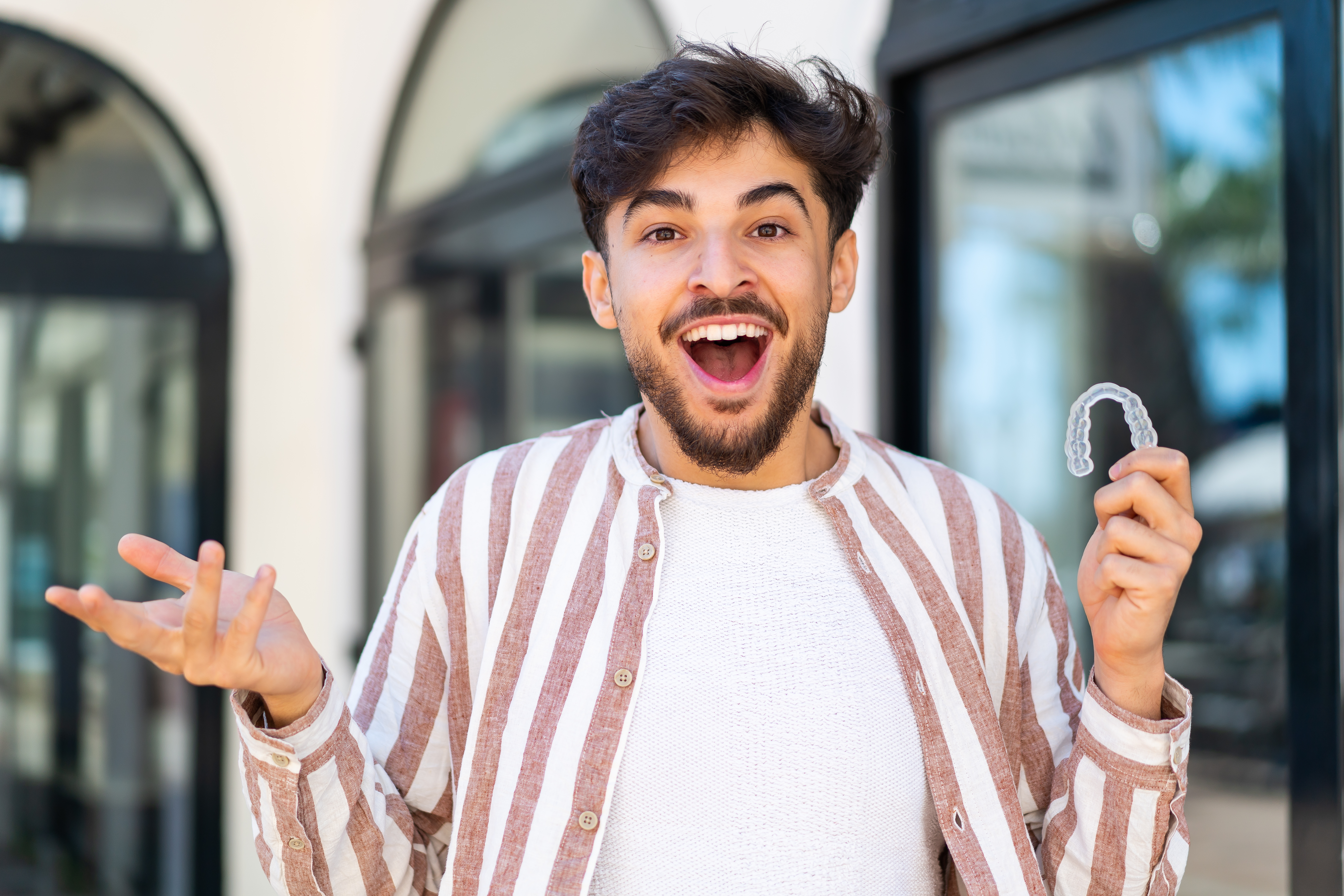 Handsome Arab man holding invisible braces at outdoors with shocked facial expression