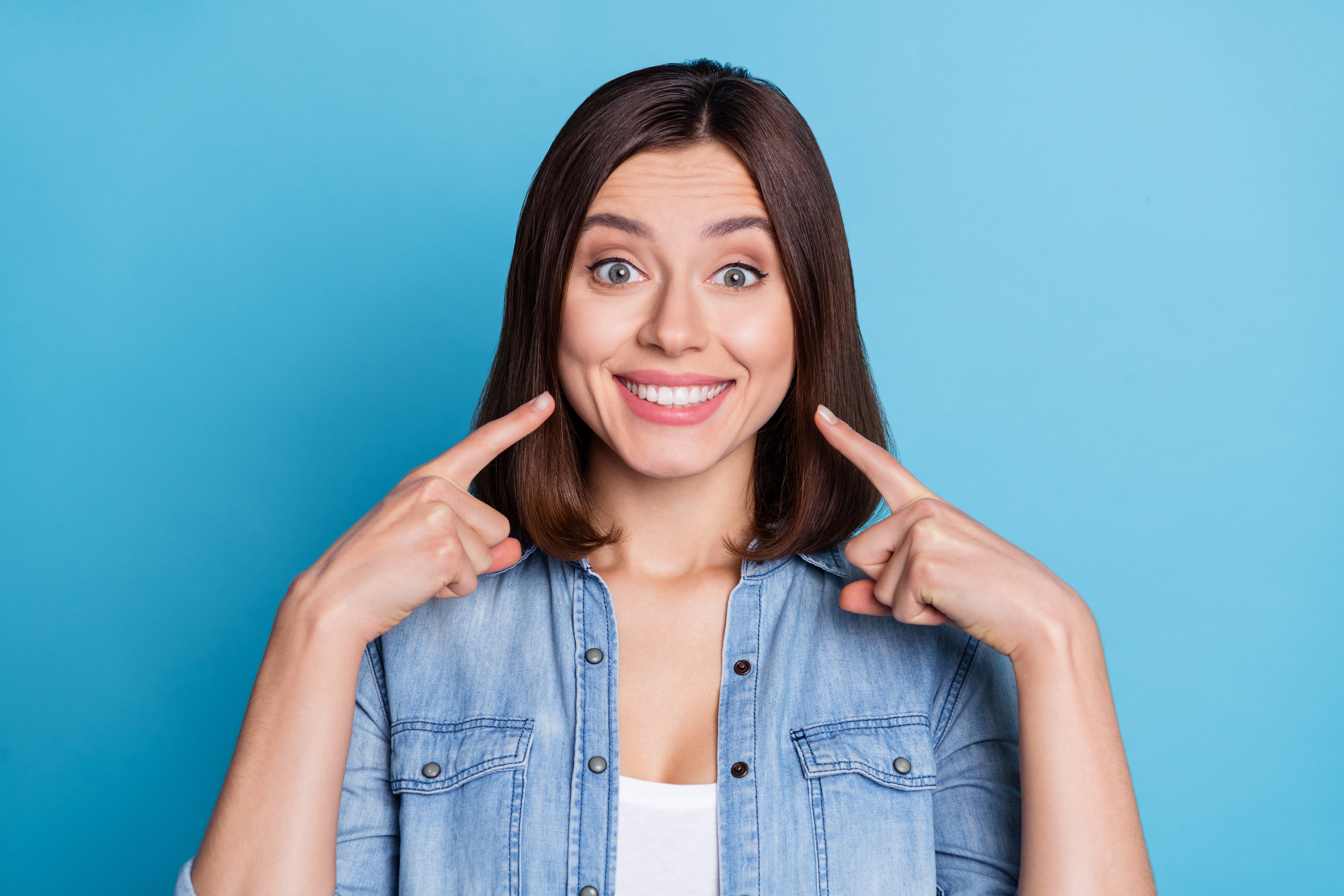 Photo of pretty adorable lady dressed denim shirt pointing fingers white teeth isolated blue color background.