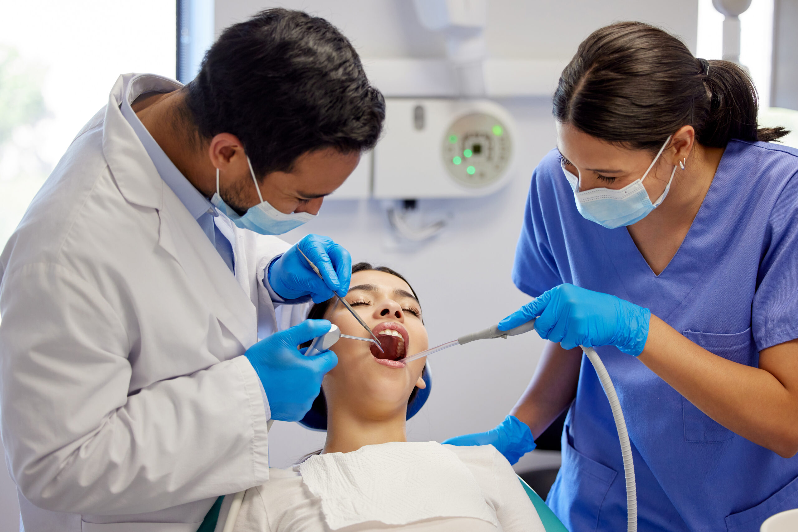 Dentist, team and oral care with patient for healthcare, wellness and teeth whitening in practice. Woman, dental professional and PPE with tools for consultation, cleaning and filling on chair.