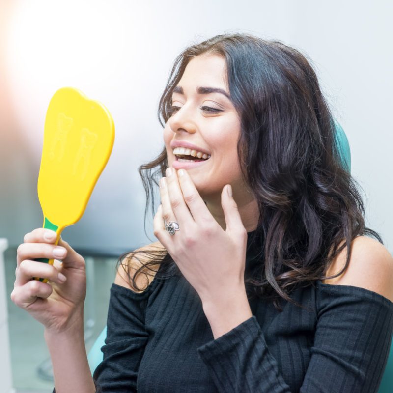 Woman looking at her teeth. Smiling lady at dentist office. Smile as a masterpiece.